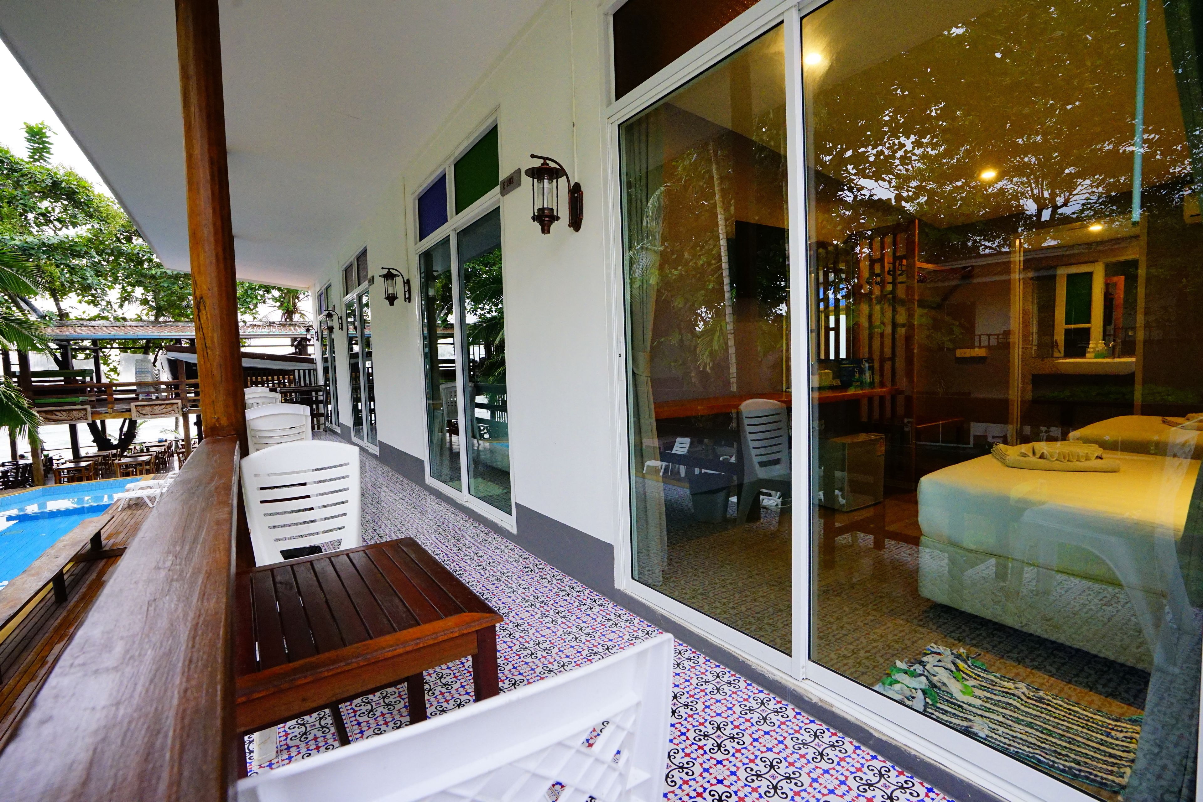 A hotel room with a large sliding glass door, a wooden table, and a pool area visible through the door.