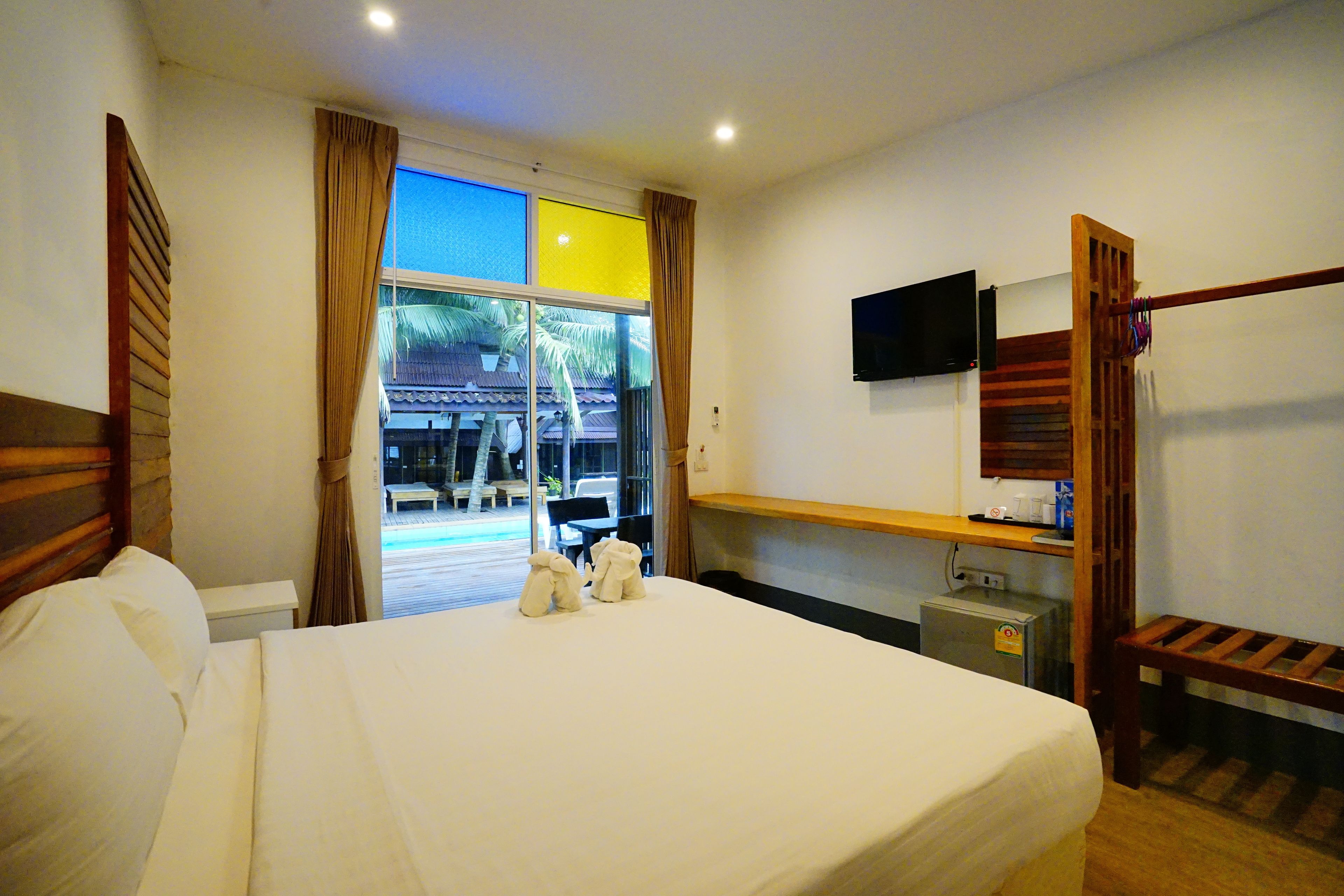 Habitación de hotel con cama, escritorio, televisor y vistas al exterior.