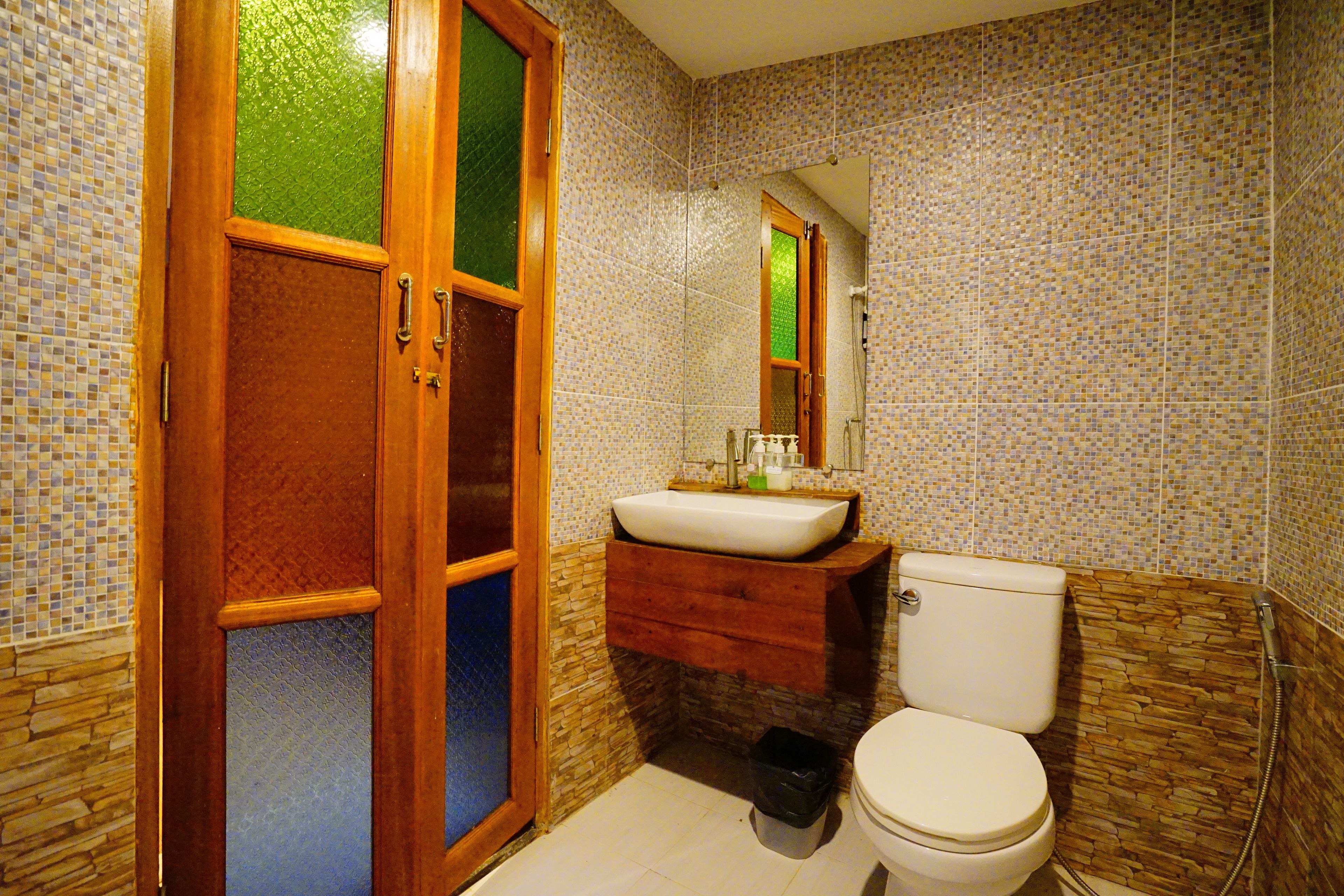 A bathroom with a wooden door, a sink, a toilet, and a shower area.