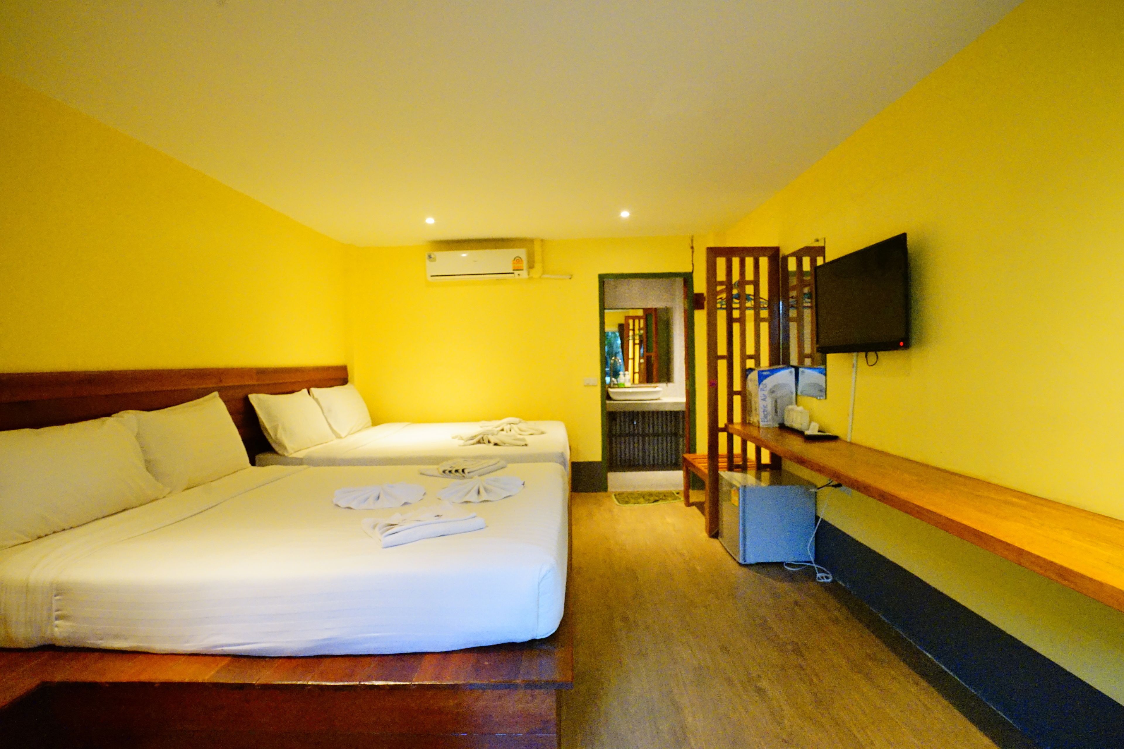 A hotel room with two beds, a TV, and a wooden bench.