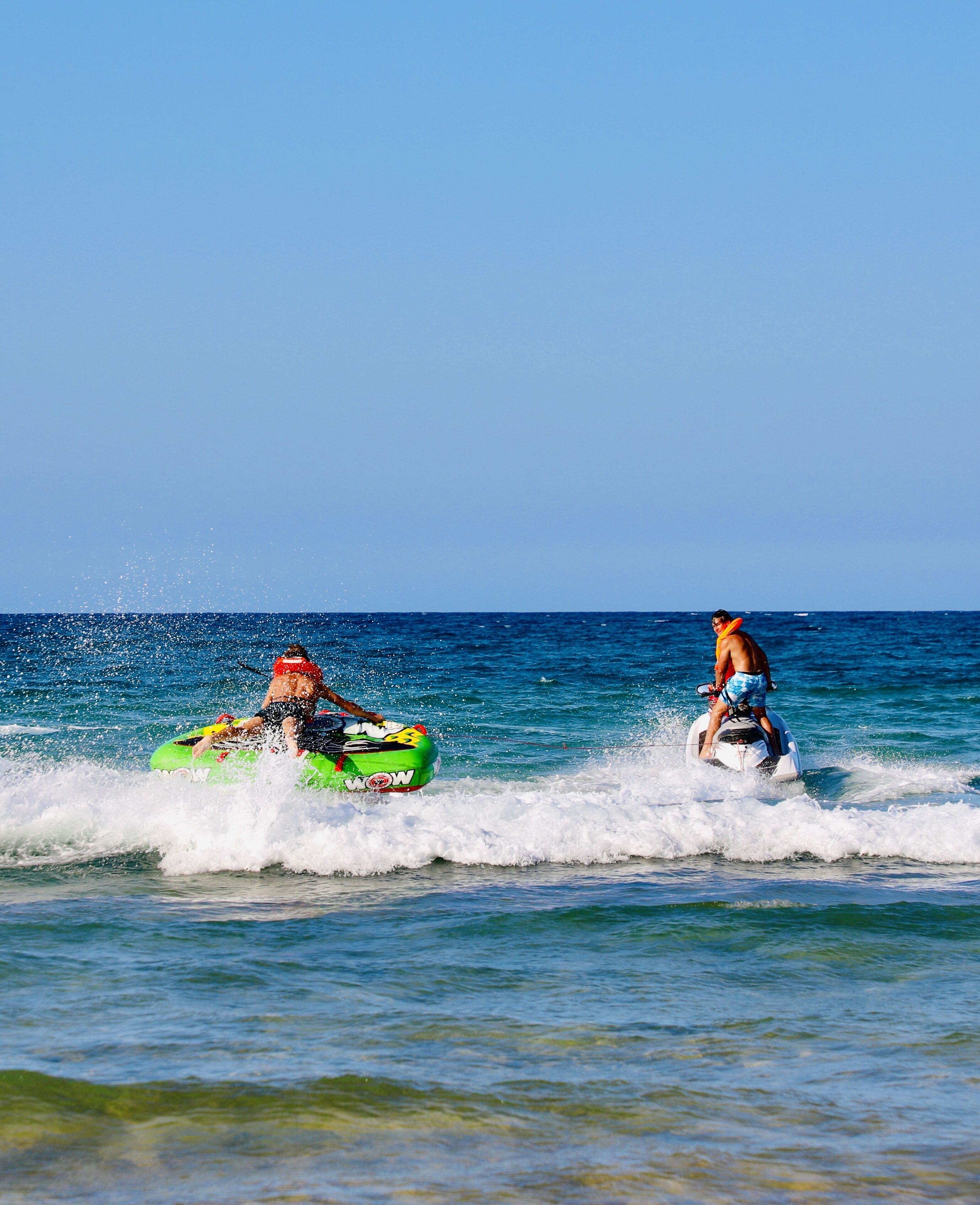 Two people jet-skiing on a clear day.