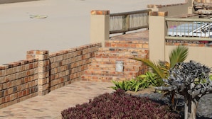 A beach with a brick wall, palm trees, and a view of the ocean.