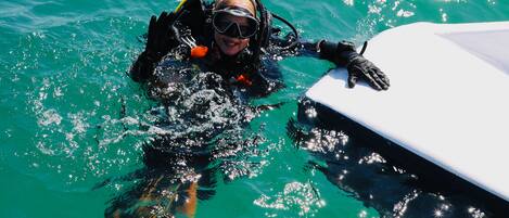Un submergit amb un neoprè i equip d'escàner a prop d'una embarcació.
