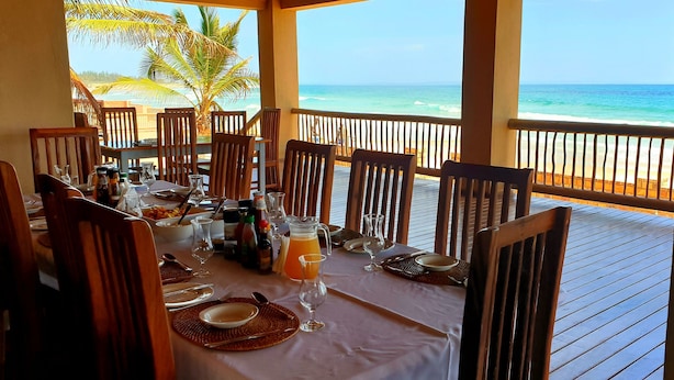 A dining table set for six with a view of the beach and ocean.