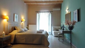 A bedroom with a bed, bedside tables, a chair, a desk, and a window with curtains. - Efi & Sofia Apartments (Corfu)