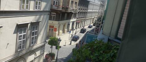 Une rue étroite, bordée de bâtiments des deux côtés, avec un passage piéton et une voiture garée.