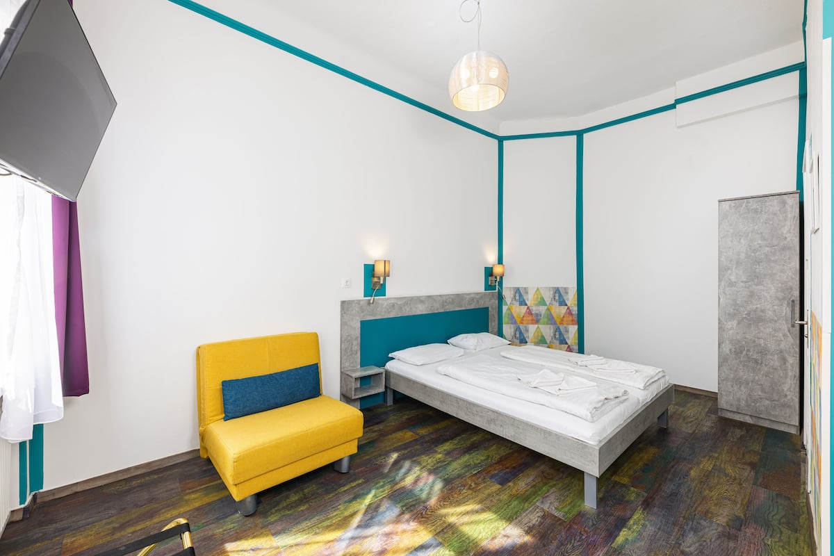 A room with a bed, a yellow sofa, a nightstand, and a wardrobe.
