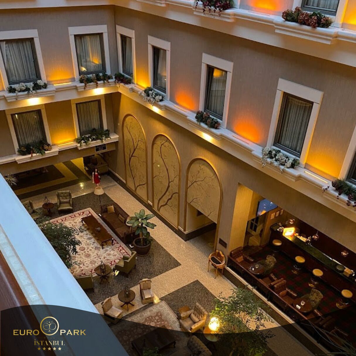 A hotel lobby with a checkered floor, multiple seating areas, and a bar.
