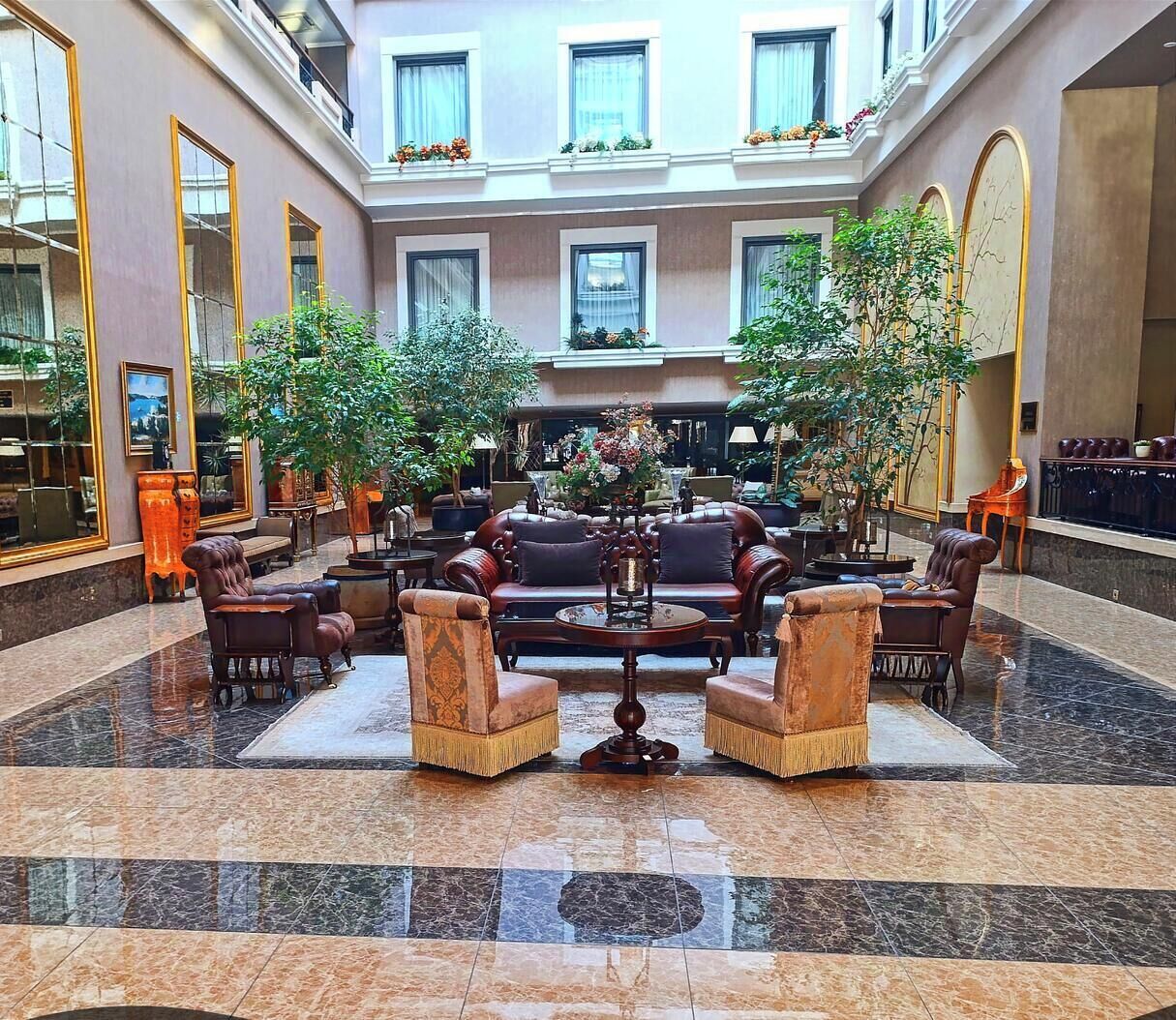 Un hall d’entrée spacieux avec un espace salon central, de grandes fenêtres et un sol en marbre.