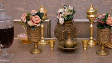Une table ornée de décorations en laiton et de verrerie, comprenant des vases avec des fleurs et une théière, le tout posé sur un comptoir en marbre.