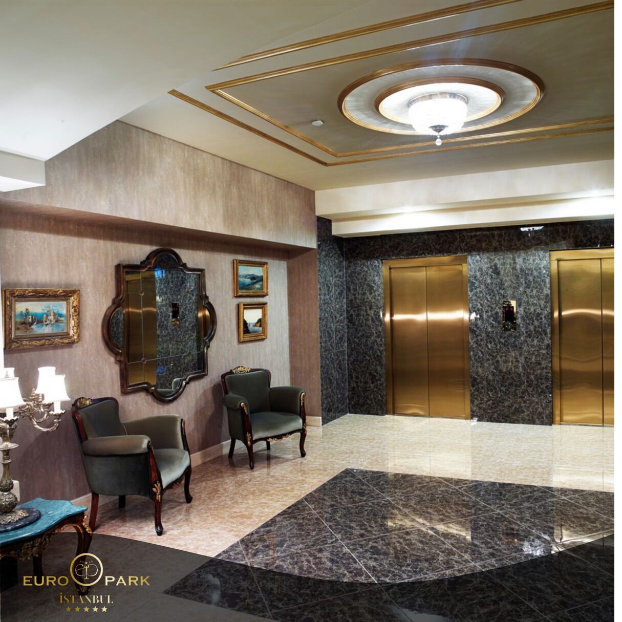 A lobby with marble flooring, two elevators, a chandelier, and framed artwork on the walls.