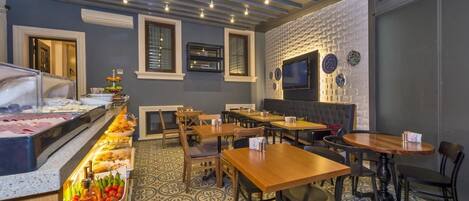 A restaurant with a buffet, seating area, and a TV mounted on the wall.