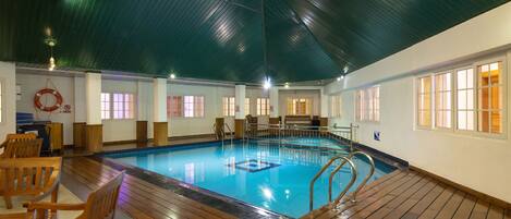 Una piscina interior con cubierta de madera, agua cristalina y techo alto.