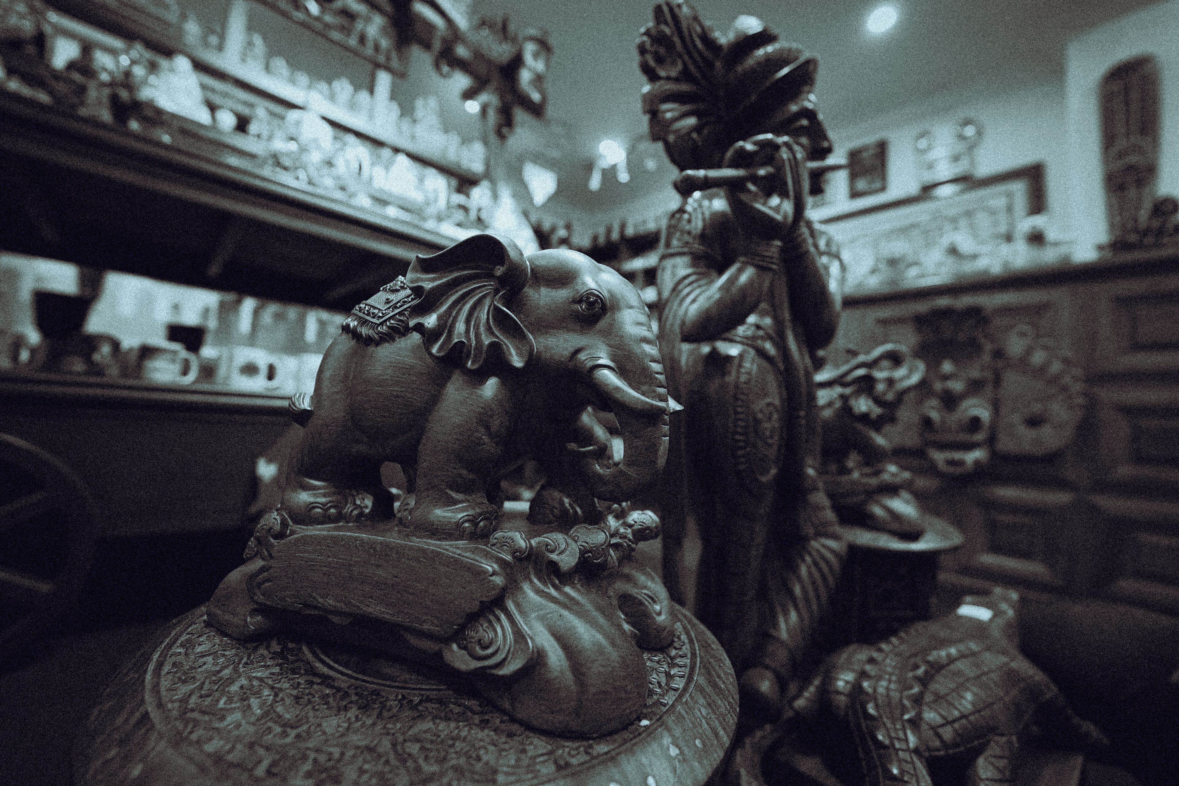 A room with a statue of an elephant and a figure holding a staff.