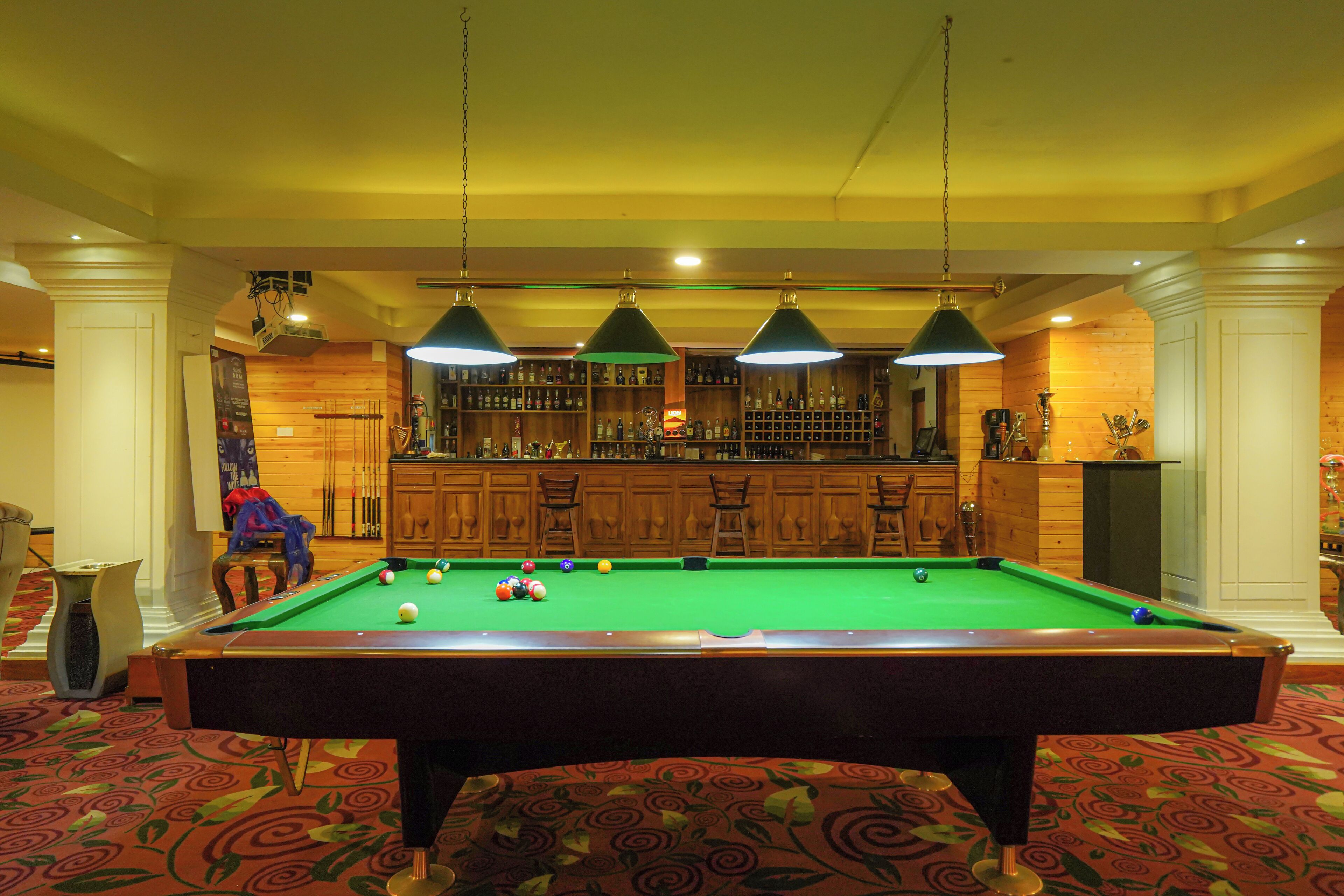 Un tavolo da biliardo con le palle, un'area bar con le bottiglie e un muro in legno.
