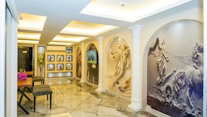 A lobby with marble floors, a reception desk, framed artwork, and a mural of a horse and rider. - Luce Suite Hotel (Istanbul)