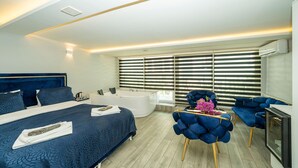 A modern bedroom with a large bed, a bathtub, and a seating area with a blue chair. - Luce Suite Hotel (Istanbul)
