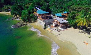 A beachfront property with multiple buildings, including a large structure with a blue roof and several smaller ones. - The Naturalist Beach Resort (Castara)