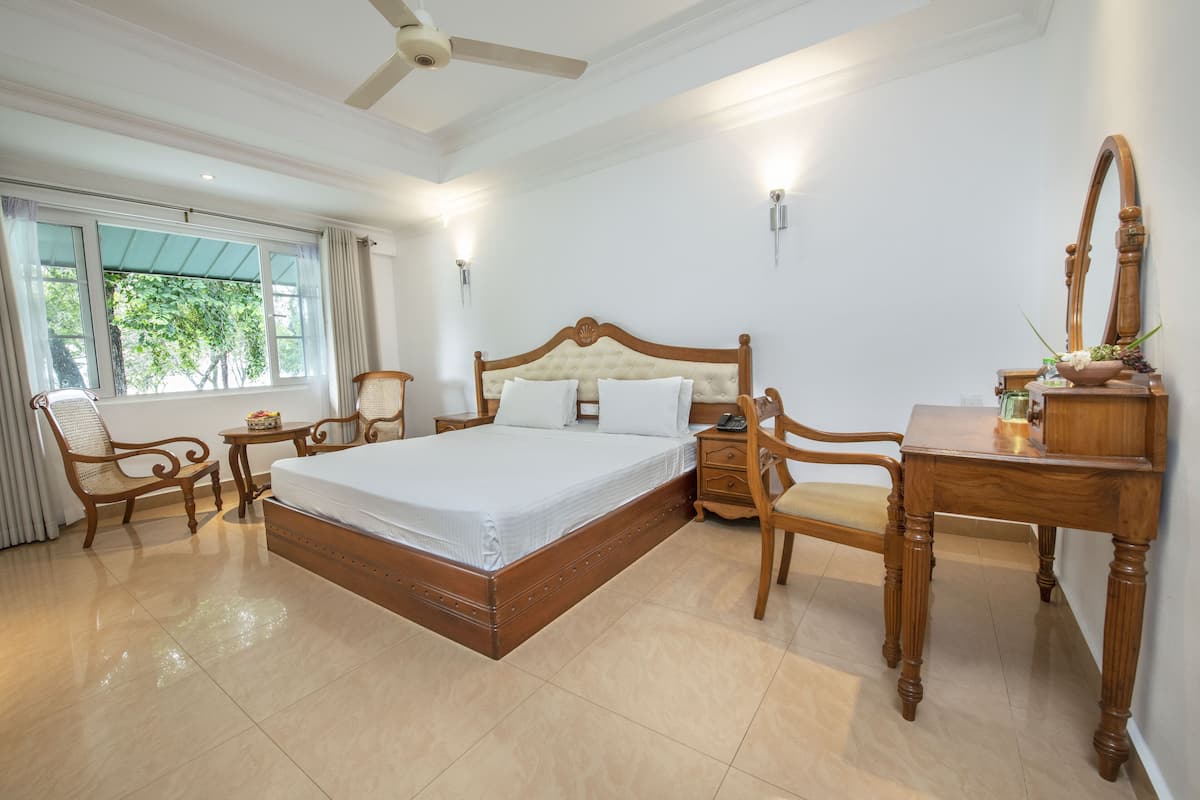 Une chambre spacieuse avec un grand lit, des meubles en bois, un bureau et une chaise.