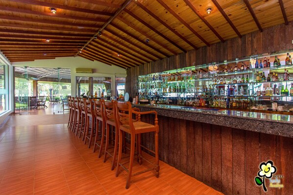 A bar area with wooden chairs and a bar counter displaying various bottles.