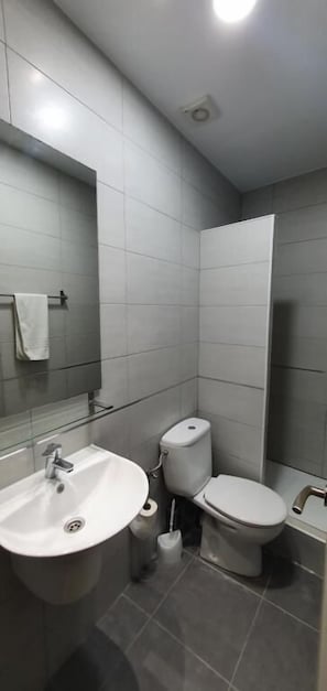 A modern bathroom with a sink, toilet, and shower.