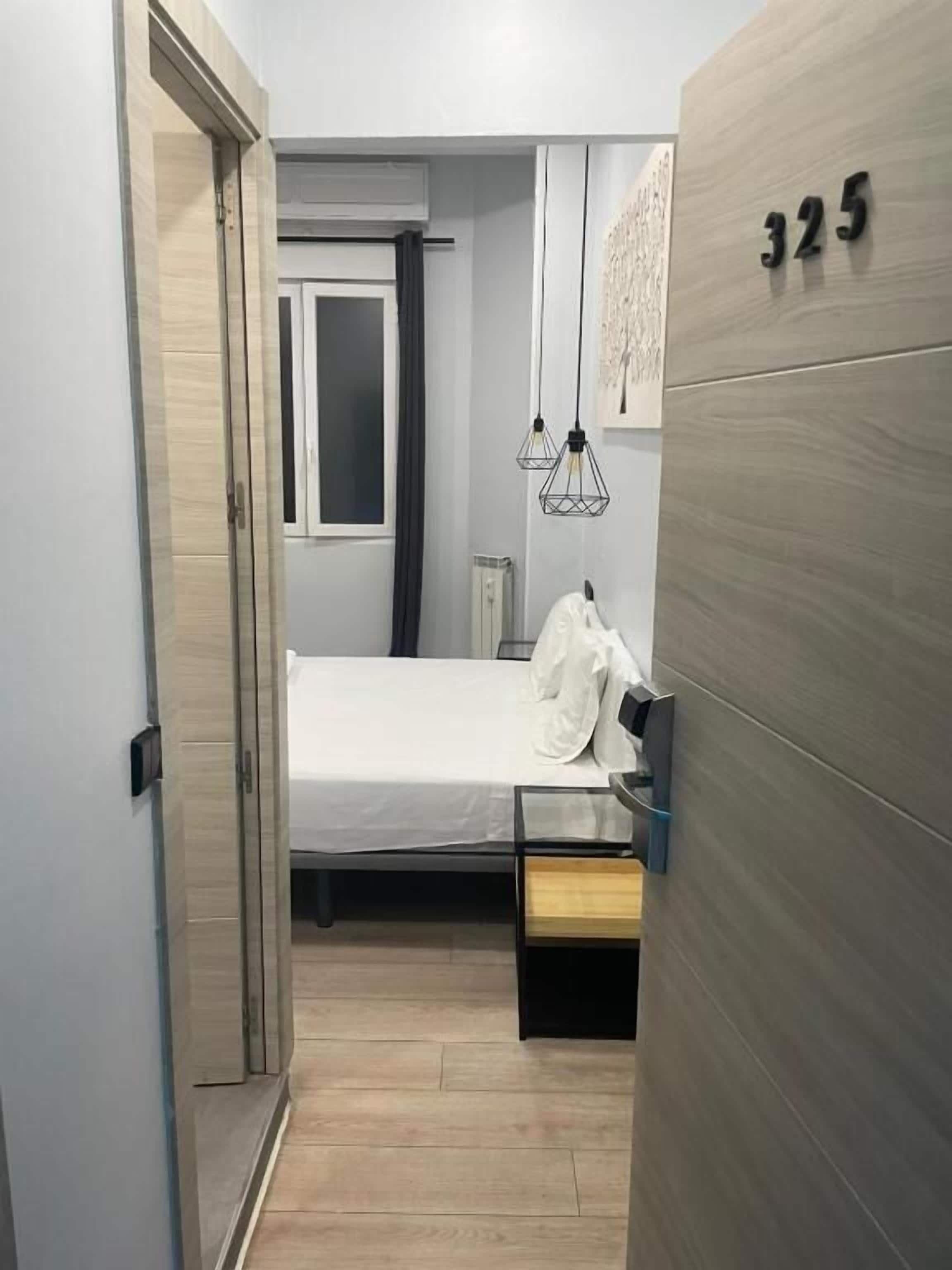 Ett hotellrum med en säng, ett sängbord, en garderob och en dörr som leder till ett annat rum.