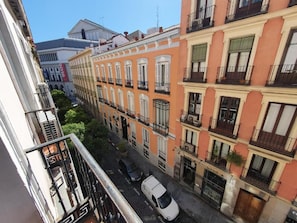 Vista de una calle con edificios de varios pisos, balcones y una camioneta blanca estacionada.