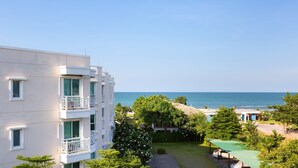 A hotel with a view of the sea, featuring balconies, a pool area, and lush greenery. - Baan Poolom Beachfront Condominium (Hua Hin)
