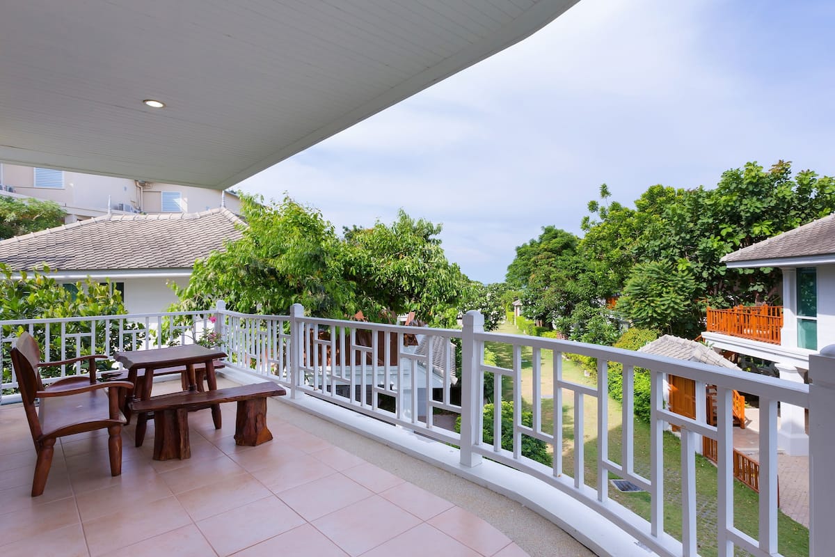 A covered balcony with a white railing, a wooden table, and chairs.