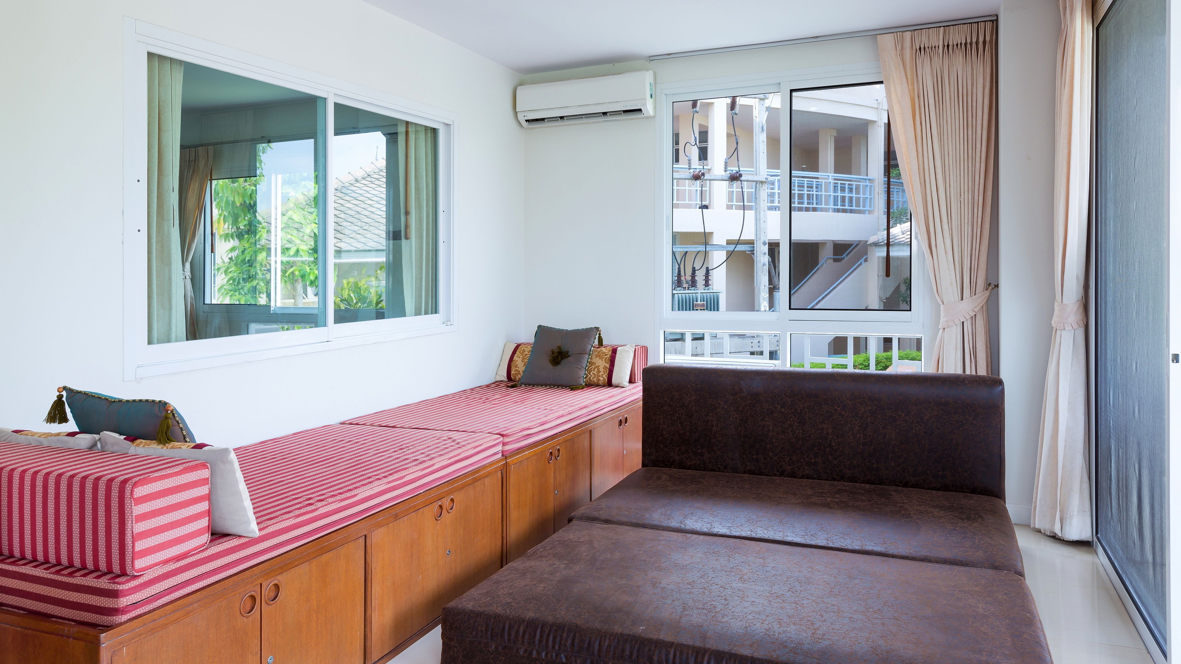 A room with a built-in bench along the window, a ceiling fan, and a view of a balcony.