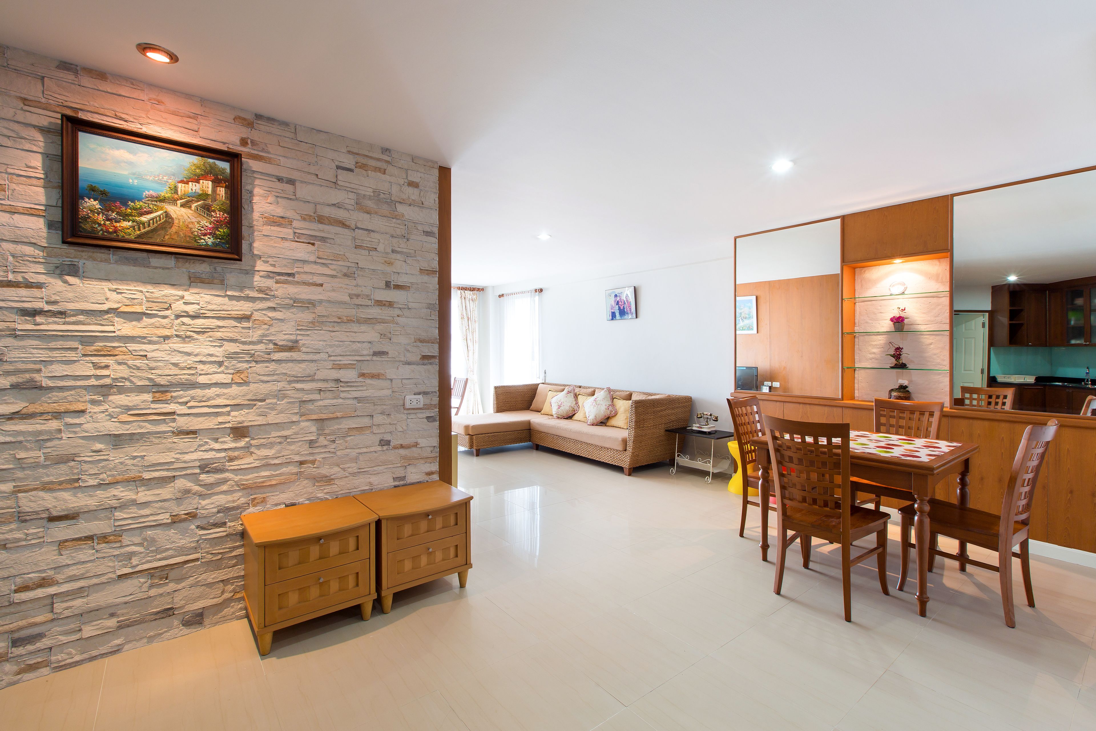 Uma sala de estar moderna com parede de pedra, um armário de madeira, um sofá e uma mesa de jantar com cadeiras.
