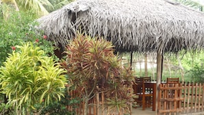 A thatched-roof structure with a wooden fence and seating area. - Beach Lagoon Guesthouse (Tangalle)