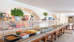 Ein reichhaltiges Buffet mit verschiedenen Speisen, einer Zimmerpflanze und einem Bild an der Wand.