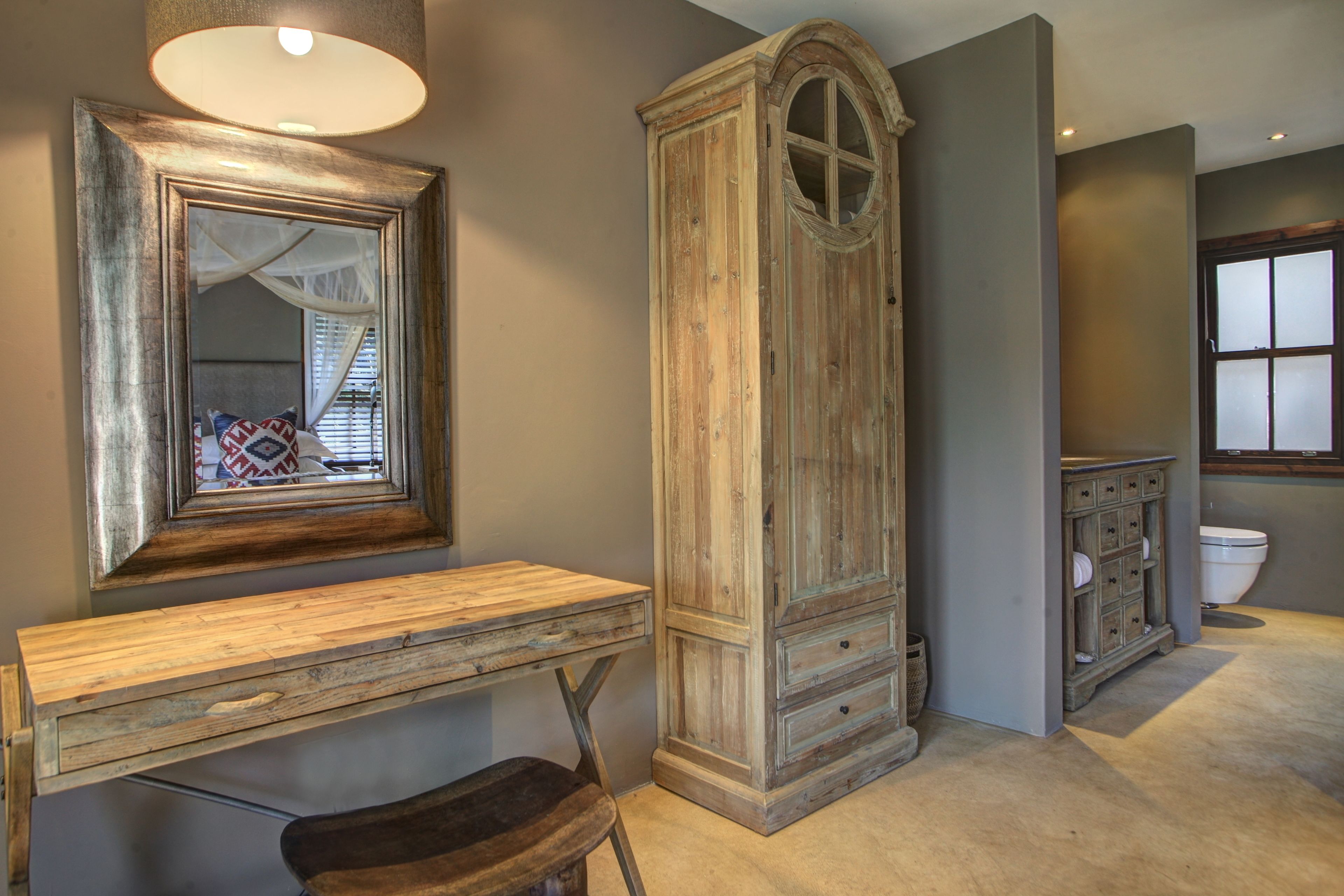 A bathroom with a wooden vanity, a mirror, a cabinet, and a toilet.