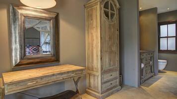 A bathroom with a wooden vanity, a mirror, a cabinet, and a toilet.