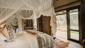 A bedroom with a large bed, a canopy, a lion painting, and a view of the outdoors.