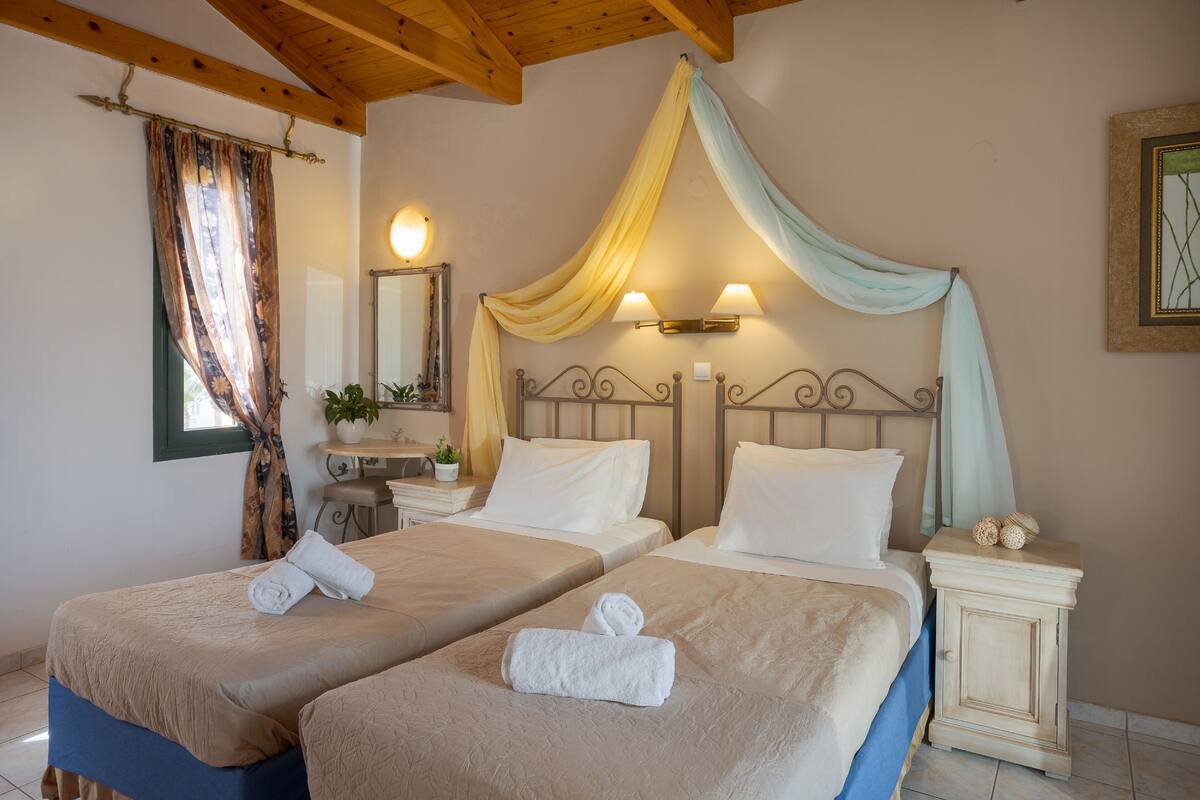 Habitación doble con dos camas, cada una con dosel, mesita de noche y espejo.
