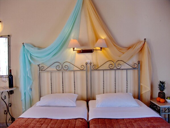 A double bed with a metal headboard, two bedside lamps, and a draped curtain. - Irida Apartments by Estia (Hersonissos)