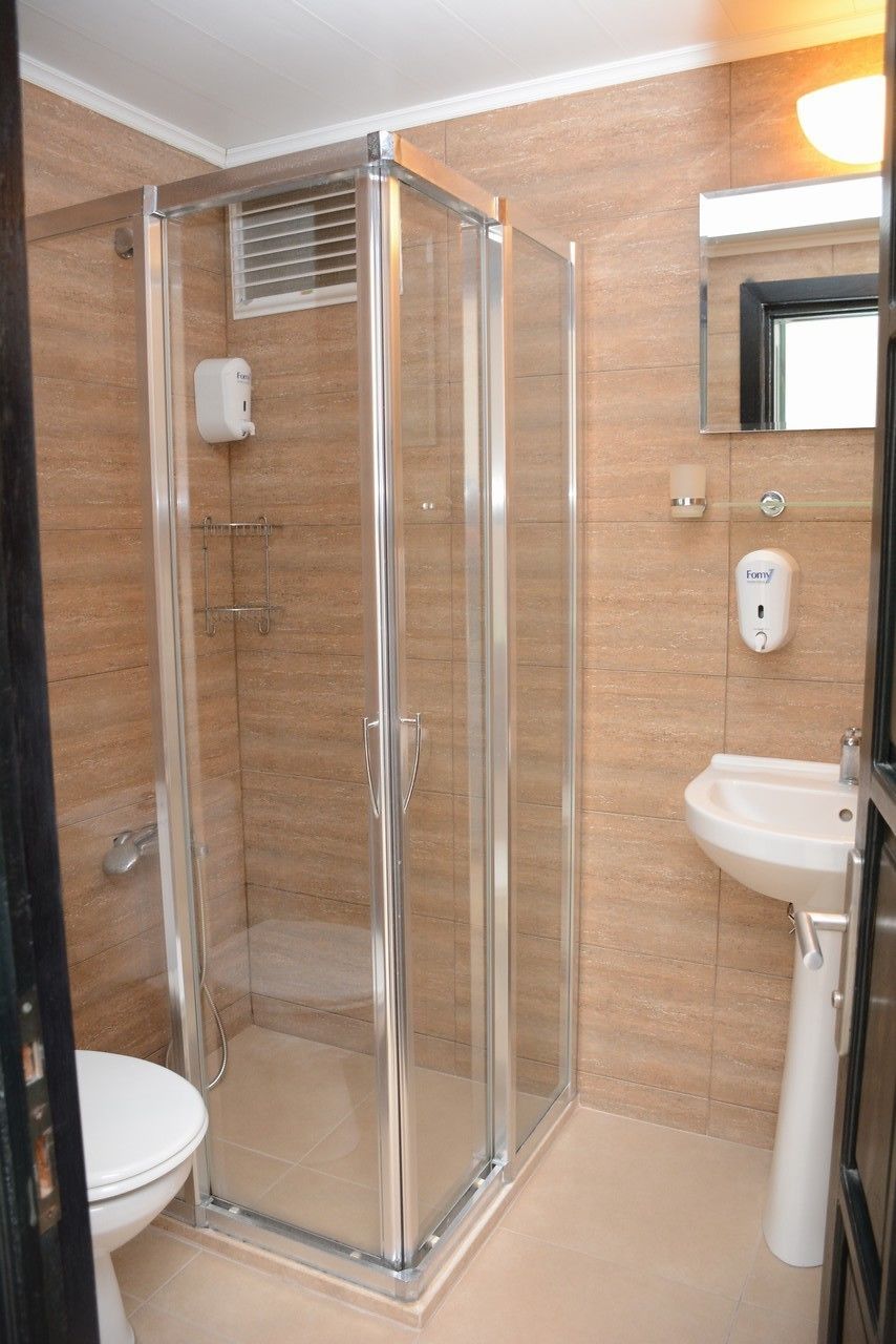 A bathroom with a glass-enclosed shower, a white sink, and a toilet.
