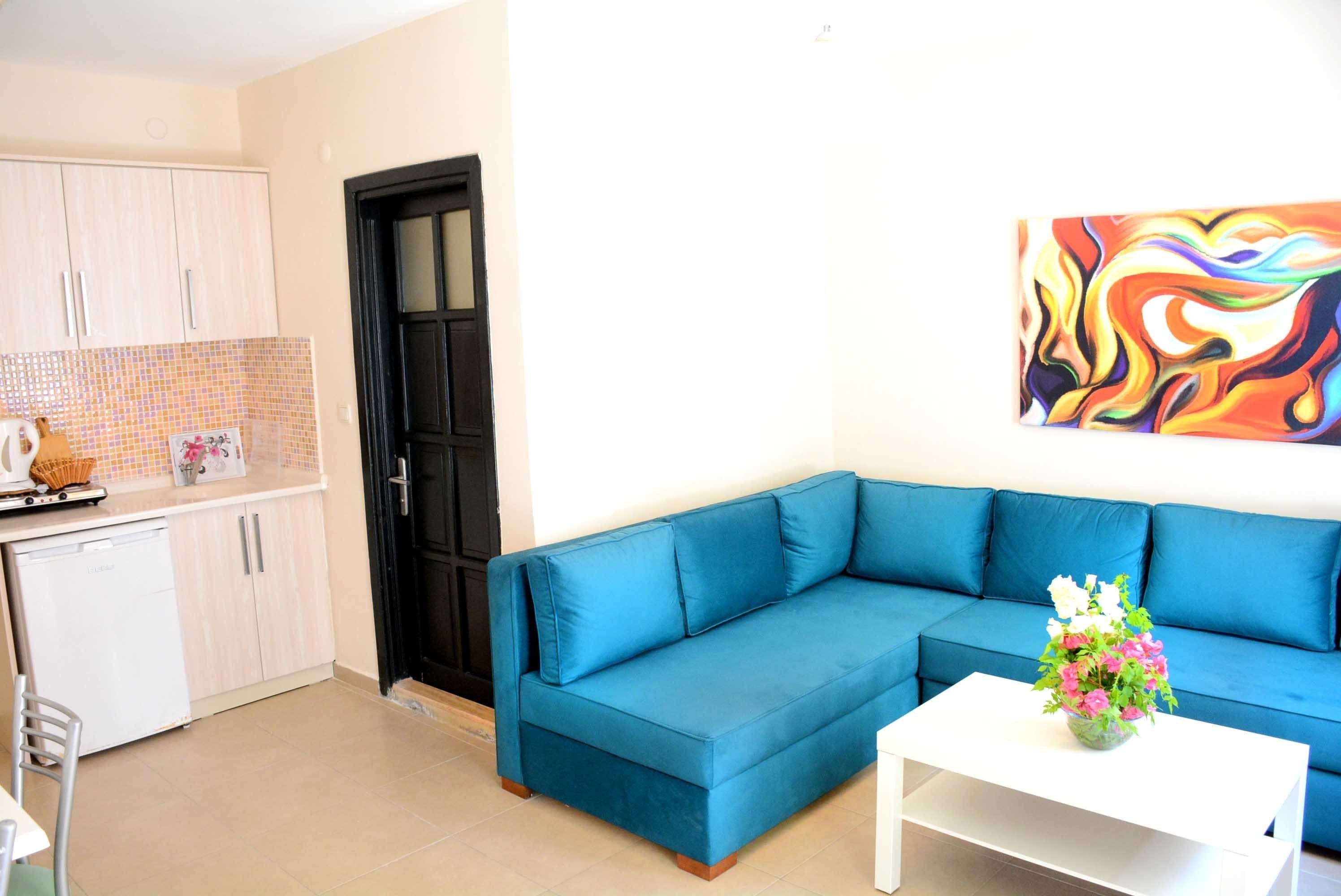 A living room with a blue sofa, a white coffee table, and a colorful abstract painting on the wall.