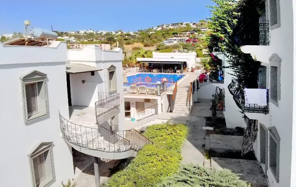 A rooftop pool area with a blue pool, surrounded by white buildings with balconies.