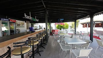 Un espace extérieur abrité, aménagé avec un bar, des chaises et des tables.