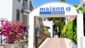 A white building with a sign reading "maison 48 APARTS" and a pathway leading to the entrance. - Maison 48 Apart Hotel (Bodrum)
