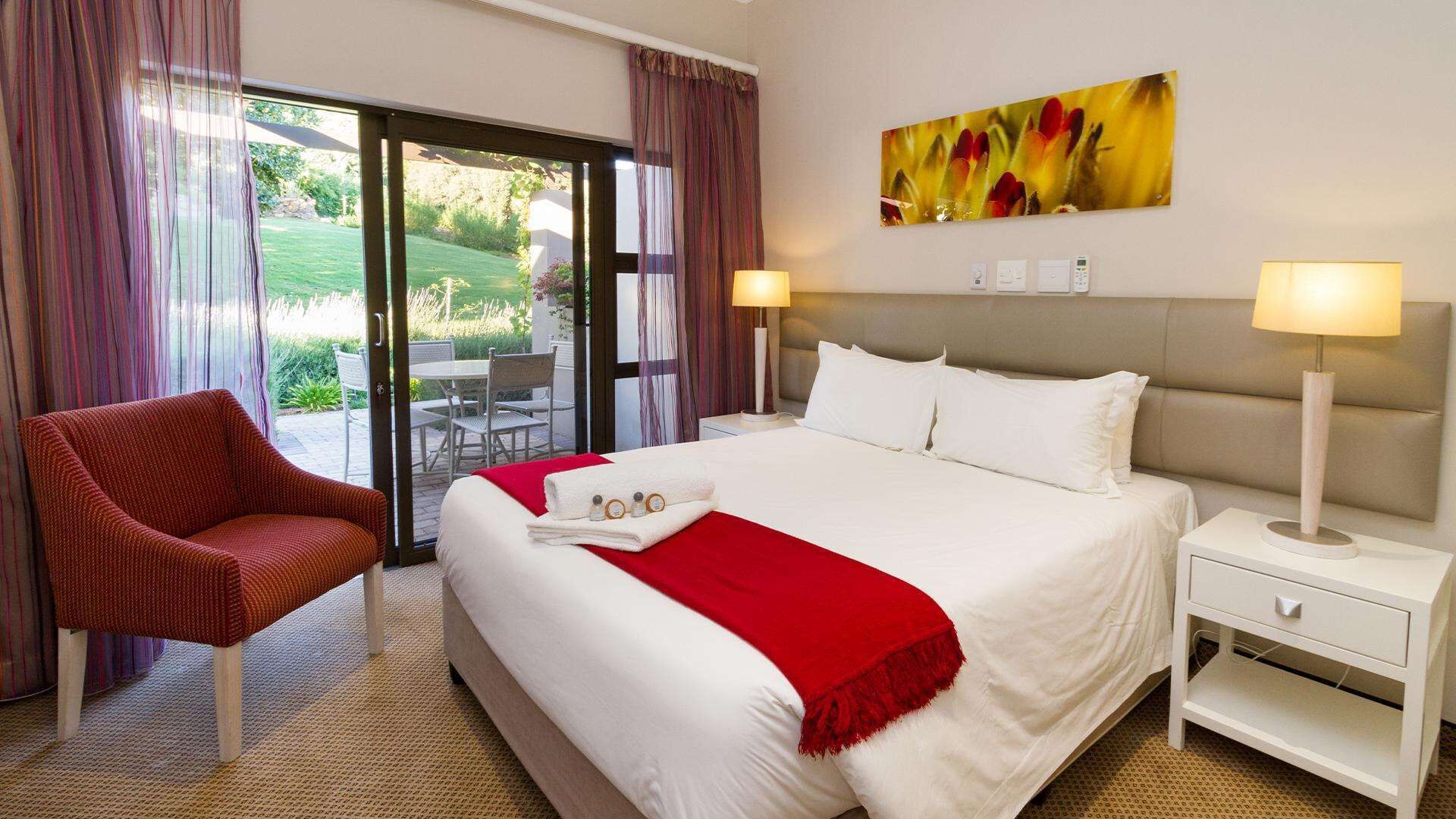 Habitación de hotel con una cama, una silla, una mesita de noche y vistas al exterior.
