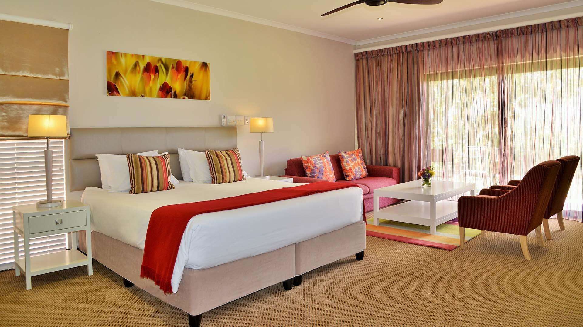 Una habitación de hotel con una cama, un sofá, una mesa de centro y una silla.