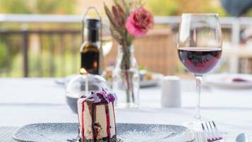 Un dessert présenté sur une assiette, accompagné d’un verre de vin rouge et d’une bouteille de vin, le tout sur une table à l’extérieur.