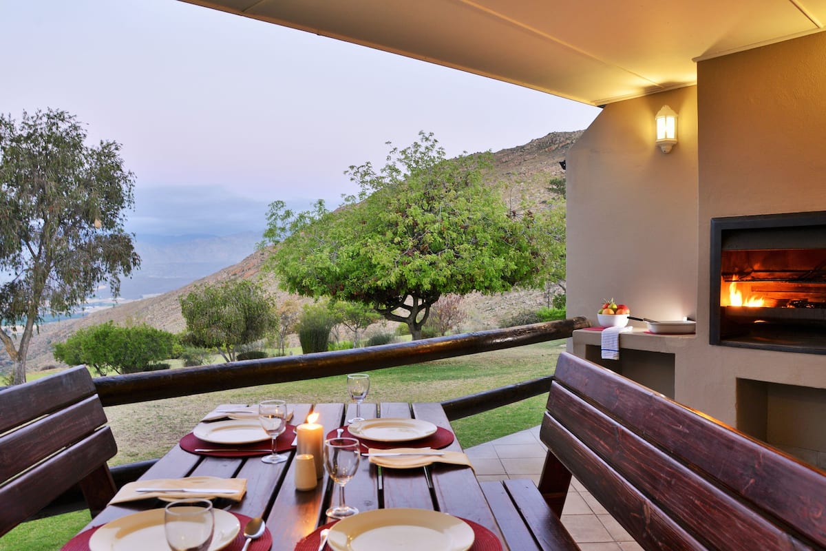 An outdoor dining area with a table set for four, a candle, and a pizza oven.
