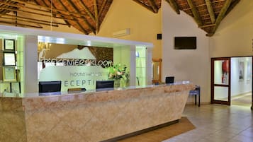 Een receptiebalie met een bord waarop staat 'Pikeknierskloof Mountain Lodge Reception' en een bord met 'DVC Member Check In'.