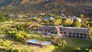 A resort with a pool, multiple buildings, and a mountainous backdrop.