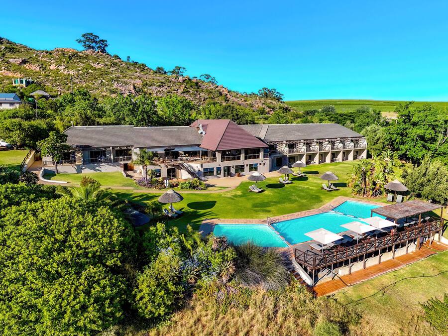 A large resort with a swimming pool, multiple guest rooms, and a well-maintained lawn.